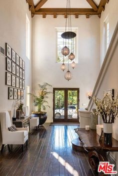 the inside of a house with wood floors and white walls, windows, and pictures on the wall