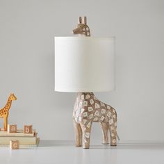 Spotted-our charming giraffe lamp, ideal as a reading light on their bedside table. The base is carved of durable mango wood in a child-safe, hand-applied rustic finish and beautifully balanced by a natural linen shade. DETAILS THAT MATTER Lamp base is expertly crafted from mango wood, featuring a Whitewashed finished. Hardware is made of die-cut mild steel finished in Brushed Nickel. On/off switch located on in-line; clear cord. White linen shade is included; interior is lined with styrene in w Giraffe Lamp, Animal Table, Wood Animal, Safari Nursery, Pottery Barn Teen, Old Wood, My New Room