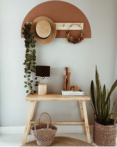 a wooden table topped with a basket next to a wall mounted shelf filled with plants