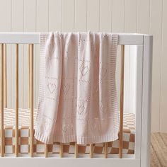 a white crib with a pink blanket on it