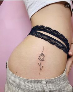 a woman's stomach with a single rose tattoo on her left side ribcage