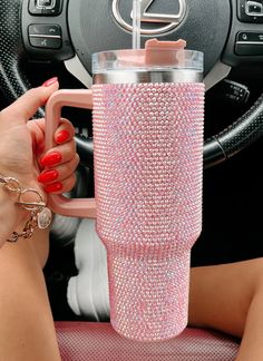 a woman is holding a cup in her hand while sitting at the wheel of a car