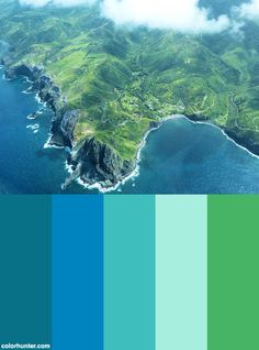 an aerial view of the ocean with green mountains in the background and blue water below