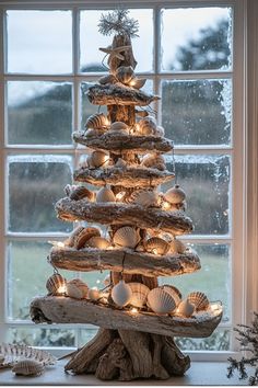 a christmas tree made out of seashells in front of a window