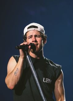 a man holding a microphone in his right hand and wearing a hat on top of his head