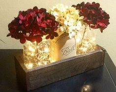 two vases filled with flowers sitting on top of a wooden table next to a wall