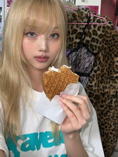 a girl with long blonde hair holding up a waffle