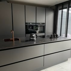 a modern kitchen with stainless steel appliances and marble counter tops, along with black blinds