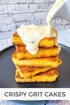 a stack of crispy grits on a black plate with a white sauce being drizzled over them