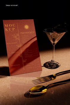 a table topped with a fork and a martini glass next to a menu on top of a counter