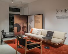 a living room filled with furniture on top of a red carpeted floor next to a white wall