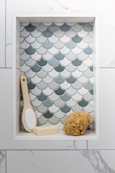 a bathroom with a white tile wall and blue mermaid scale tiles on the shower walls