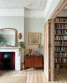 a living room filled with furniture and a fire place in front of a book shelf