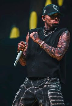 a man with tattoos on his arm holding a microphone