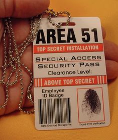 a hand holding an identification card with a chain attached to the tag that says area 51 top secret installation special access security pass clearance level