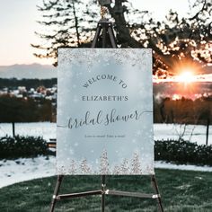 a welcome sign for the bride and groom in front of snow covered trees at sunset