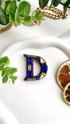 a white plate topped with orange slices and a blue letter brooch