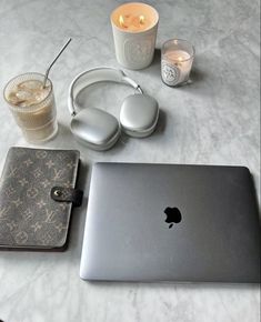 an apple laptop sitting on top of a table next to headphones and a drink