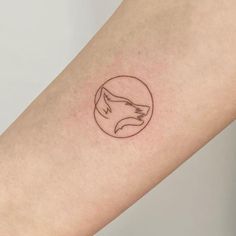 a woman's arm with a small tattoo of a fox in a circle on it