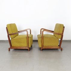 a pair of chairs sitting on top of a tile floor next to each other in front of a white wall