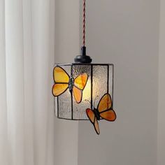 a light hanging from a ceiling with three butterflies on it's glass coverings