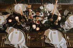 the table is set with white and gold plates, silverware, and floral centerpieces