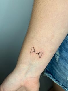 a small bow tattoo on the left inner wrist is shown in black ink, with an outline of a bow at the top