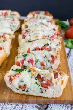 sliced pizza on wooden cutting board with tomatoes and spinach in the backgroud