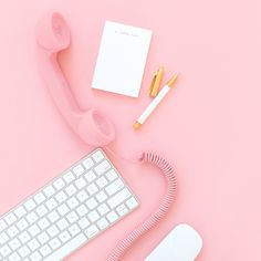 an office desk with a keyboard, phone and other items on pink paper next to it