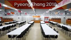 tables and chairs are set up in an empty room with a sign that reads pyeongchang 2018