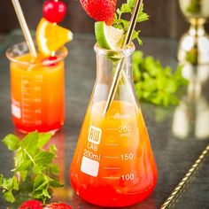 a pitcher filled with liquid and strawberries on top of a table next to another jug