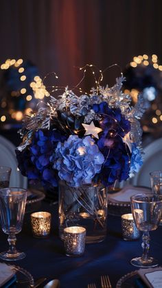 a centerpiece with blue hydrangeas and silver stars is displayed on a table