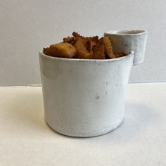 a white cup filled with food sitting on top of a table