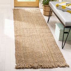 a large rug is on the floor next to a bench and potted plant in front of a window