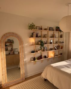 a bed room with a neatly made bed and a large mirror on the wall next to it