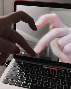 two hands are touching the screen of a laptop