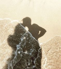 a shadow of a person standing on the beach