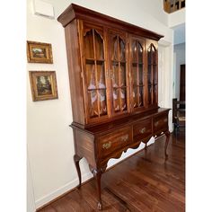 a wooden cabinet sitting on top of a hard wood floor next to a white wall