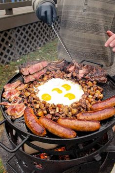 a man is cooking eggs and sausages on an outdoor grill