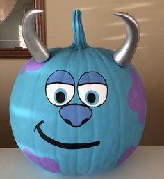 a blue pumpkin with horns and eyes painted on it's face, sitting on a table