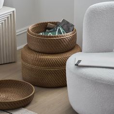 two woven baskets sitting on the floor next to a white chair and ottoman in a living room