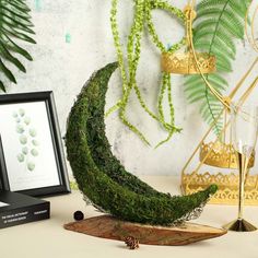 a moss covered crescent sits on a table next to a framed photograph and candle holder