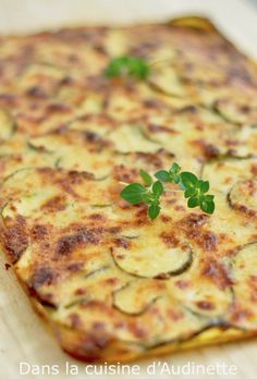 a square casserole with zucchini and parsley on top, sitting on a cutting board