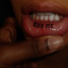 someone has written the word kiss me on their tongue and is holding it up to their mouth