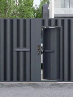 an entrance to a modern house with black doors and metal slats on the sides