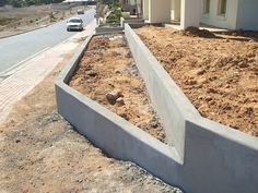 a concrete planter in front of a house with cars parked on the street behind it