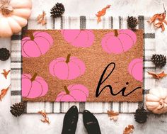 a pink door mat with pumpkins and pine cones on it next to black shoes