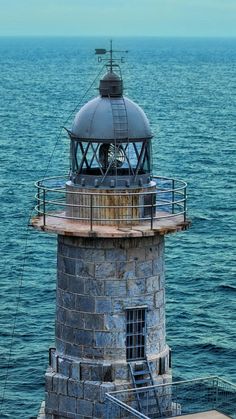 an old light house sitting on top of a pier next to the ocean in front of a boat