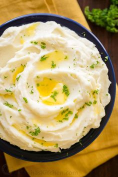 a bowl filled with mashed potatoes on top of a yellow napkin next to parsley