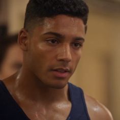 a close up of a person wearing a tank top and looking at the camera with a serious look on his face